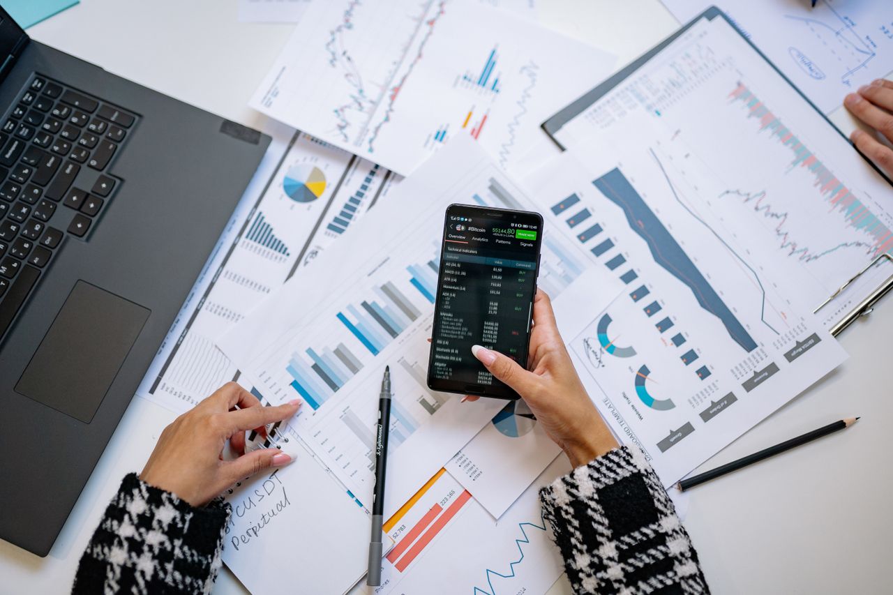 Une vue plongeante sur des graphiques et un smartphone dans un bureau, mettant en avant l’analyse de données.